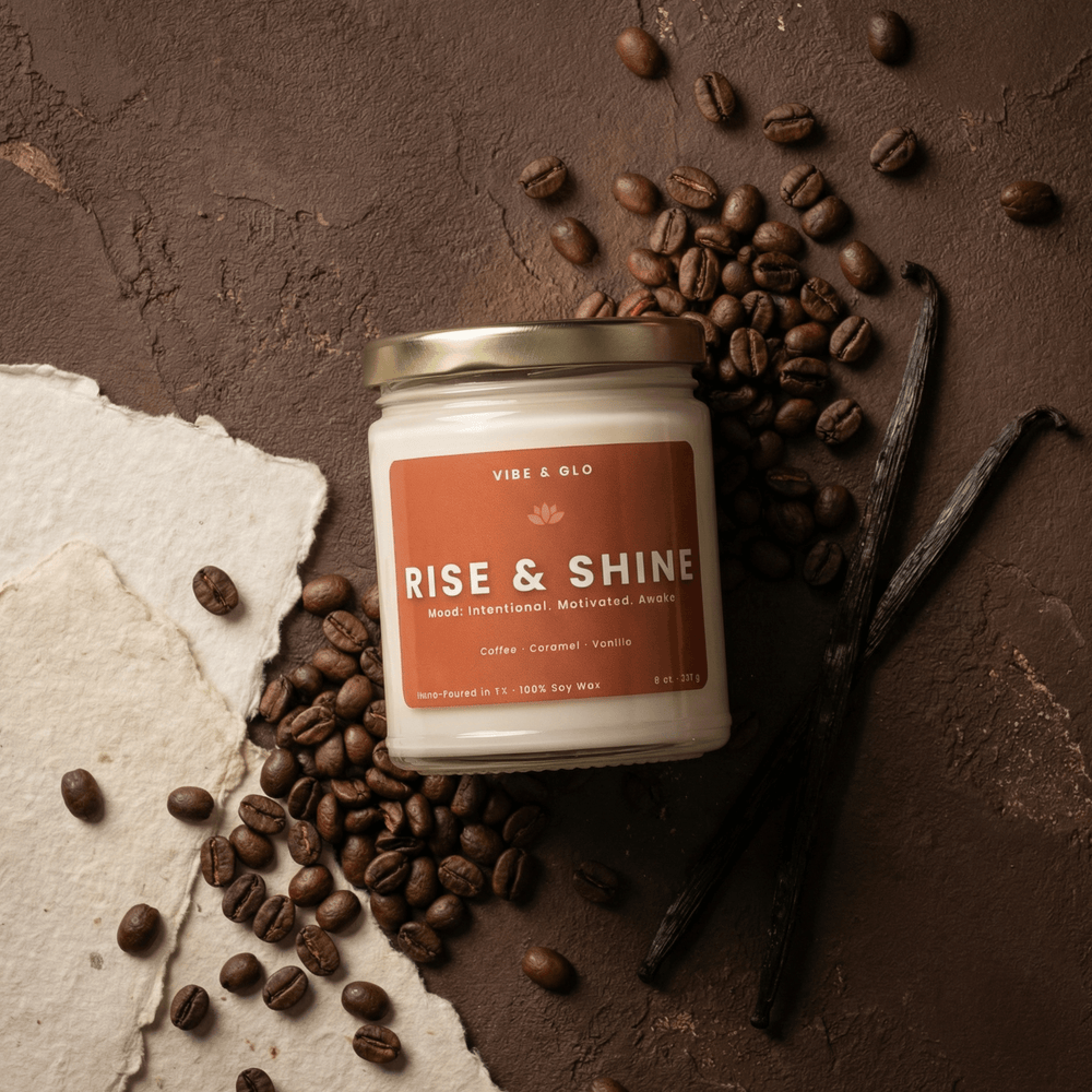 Rise & Shine 8 oz soy candle by Vibe & Glo featuring coffee, caramel, and vanilla surrounded by espresso beans and vanilla pods in a cozy flatlay.