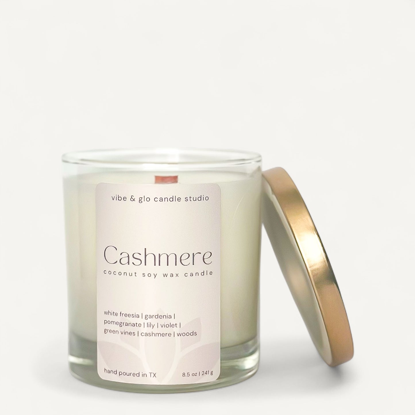 White Freesia and Soft Woods Cashmere candle in a glass jar with gold lid, hand-poured soy wax.
