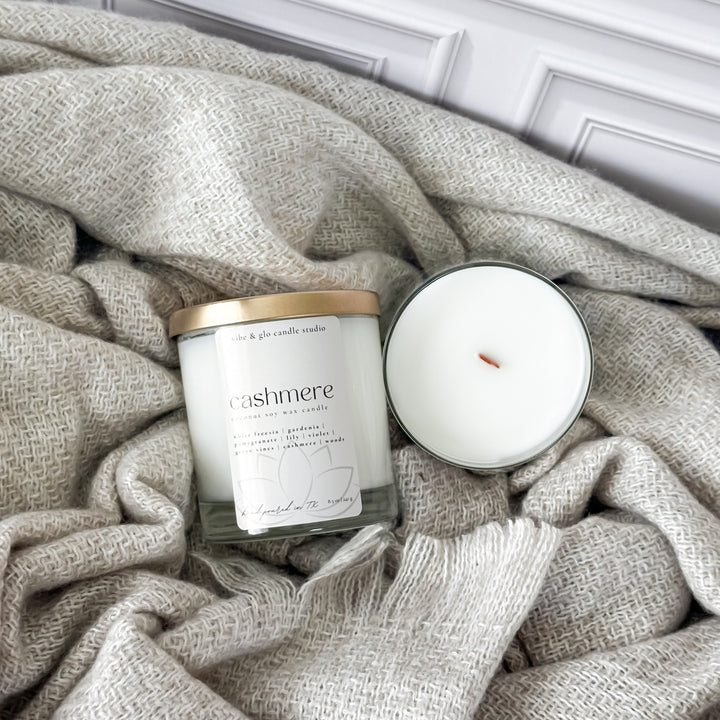 Cashmere white freesia and soft woods wood wick candle beside a plush blanket, evoking comfort and elegance.