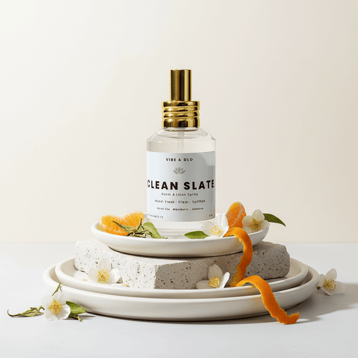 Spray bottle labeled 'Clean Slate' on a decorative stand with flowers and stones.