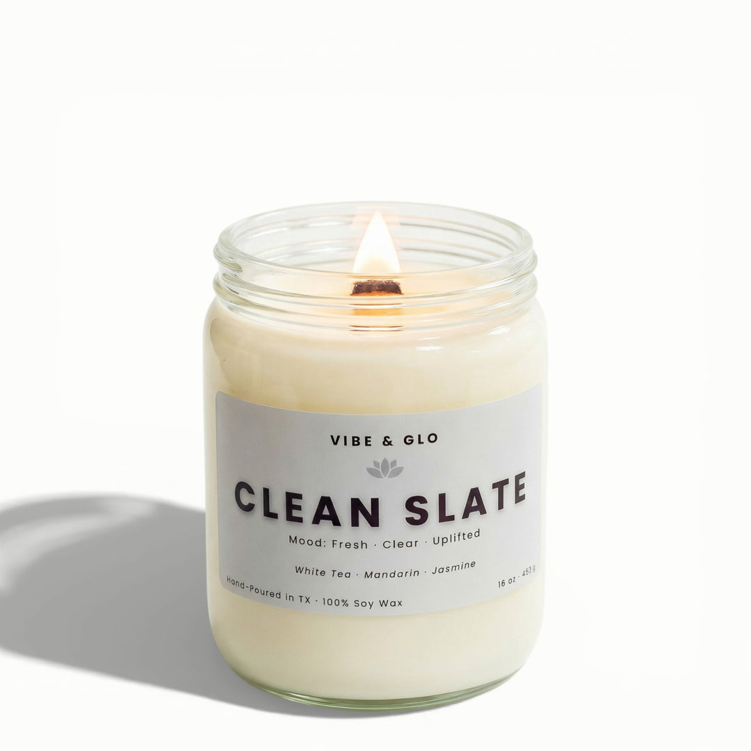 Clean Slate 16 oz wooden wick soy candle by Vibe & Glo with white tea, mandarin, and jasmine, lit wooden wick in clear glass jar, high-key studio product photo.