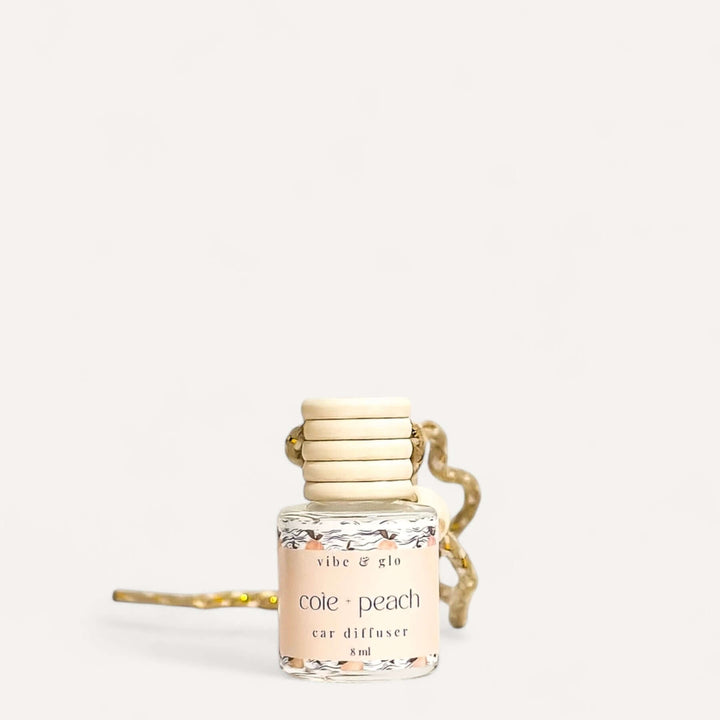 Refillable peach car air freshener diffuser in elegant glass bottle with a stylish rope hanging attachment.