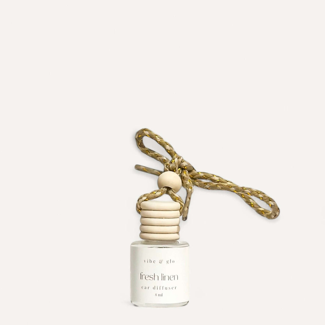 Refillable car air freshener in fresh linen scent with elegant design and hanging cord.