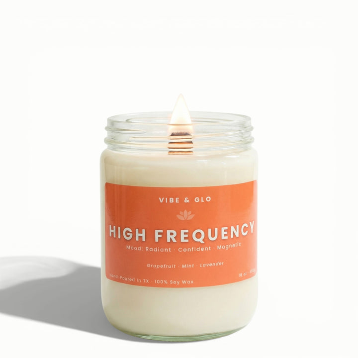 High Frequency 16 oz wooden wick soy candle by Vibe & Glo with grapefruit, mint, and lavender, lit wooden wick in clear glass jar, front-facing studio image with soft shadow.