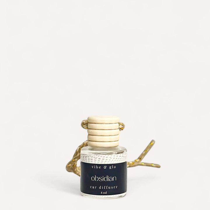 Refillable car air freshener in elegant glass design with natural wood beads, labeled 'Obsidian' fragrance.