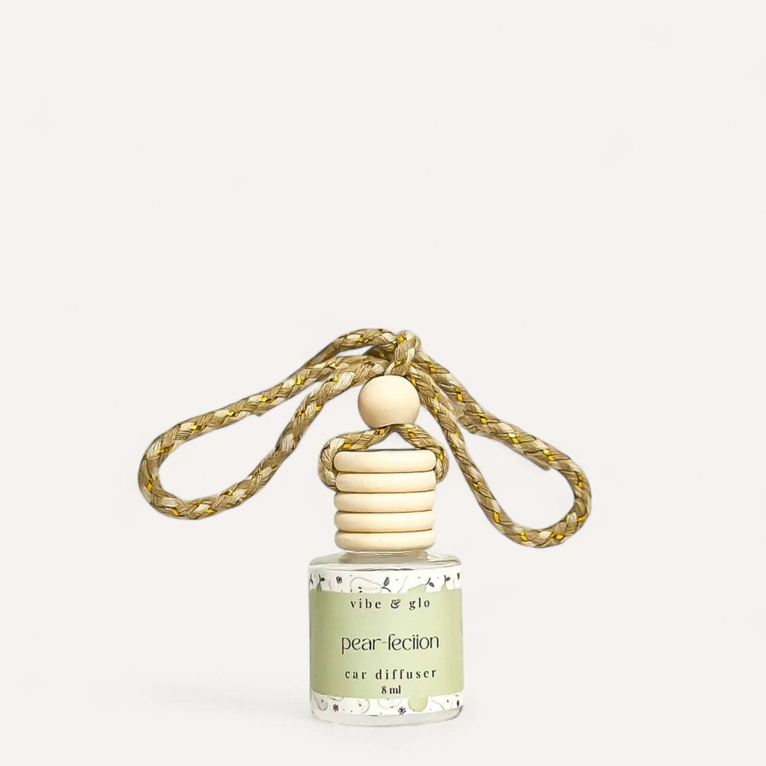 Refillable car air freshener diffuser with a wooden top and gold rope, featuring a pear scent label.