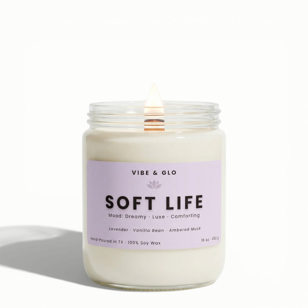 Soft Life 16 oz wooden wick soy candle by Vibe & Glo with lavender, vanilla bean, and ambered musk, lit wooden wick in clear glass jar, front-facing product image.