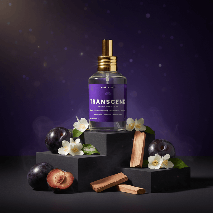 Perfume bottle labeled 'Transcend' with plums and flowers on a dark background
