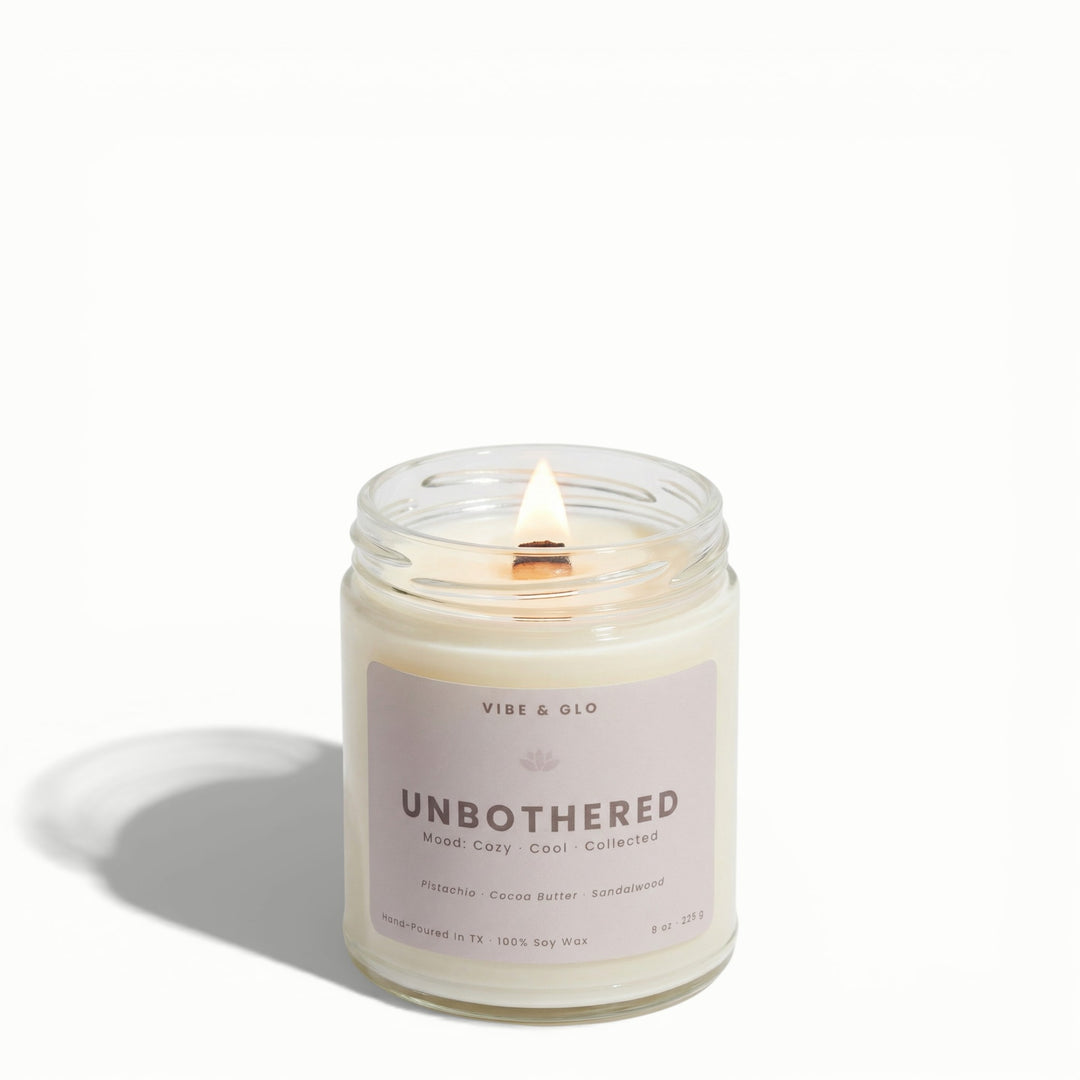 Unbothered wooden wick soy candle by Vibe & Glo with pistachio, cocoa butter, and sandalwood in clear 8 oz glass jar.