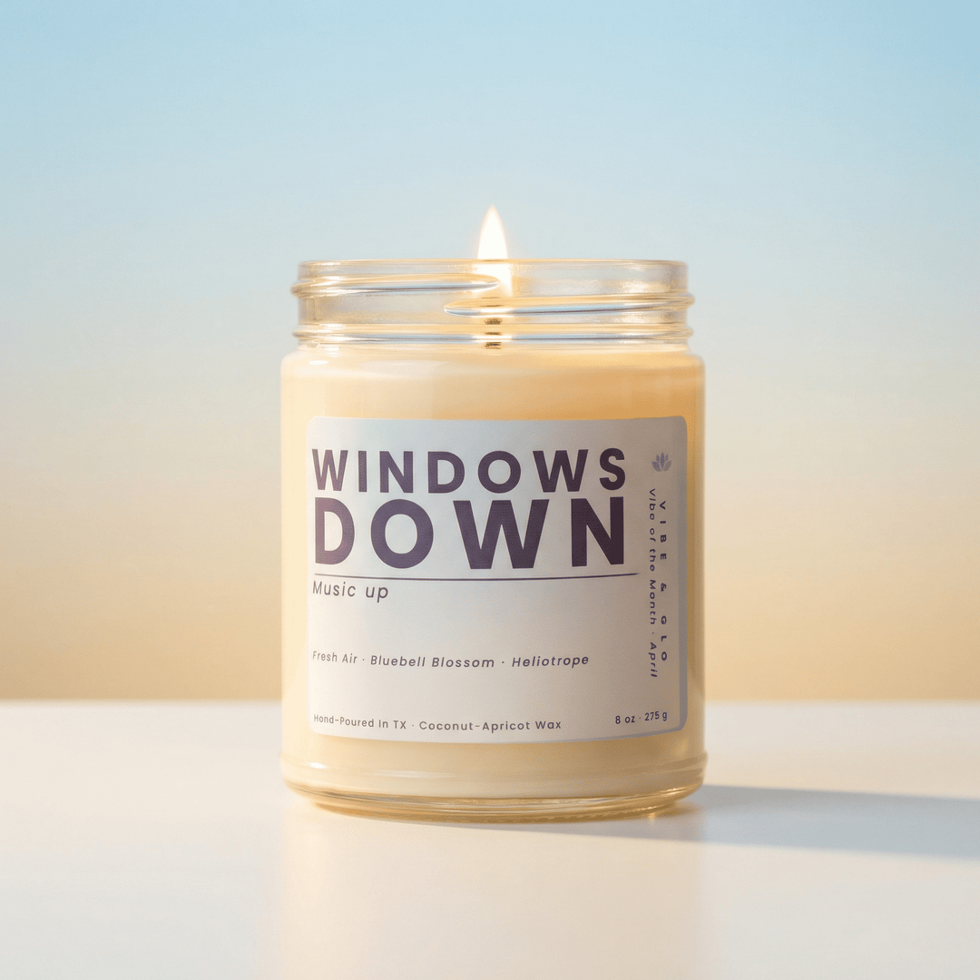 Windows Down April 2026 candle of the month by Vibe & Glo burning with a soft glow, clean coconut apricot wax candle in glass jar with minimalist label